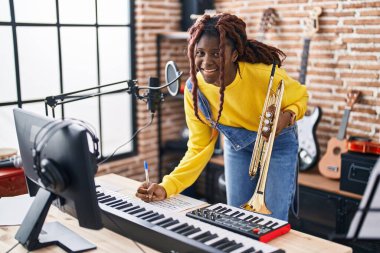 Afrikalı Amerikalı kadın müzisyen müzik stüdyosunda trompet besteliyor.