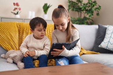 Sevimli kız ve oğlan evdeki kanepede oturuyor.