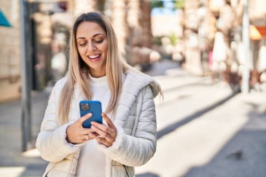 Sokakta akıllı telefon kullanan kendine güvenen genç bir kadın.