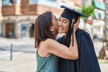 İki kadın anne ve mezun kız sokakta öpüşüyor.