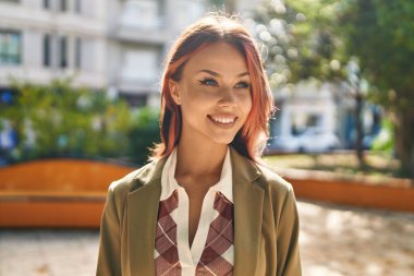 Beyaz bir kadın gülümsüyor parkın kenarına bakıyor.