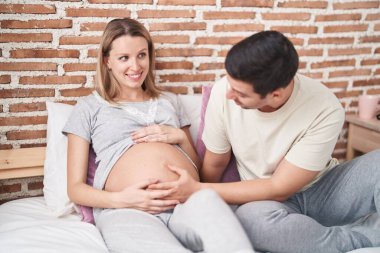 Kadın ve erkek, yatak odasında göbeğe dokunuyor.