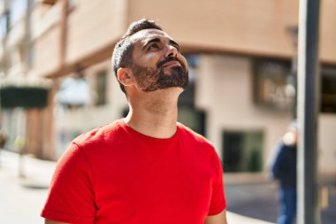 Young hispanic man smiling confident looking to the sky at street