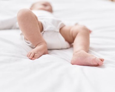 Adorable caucasian baby lying on bed at bedroom