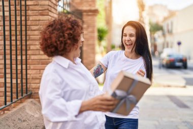 Two women mother and daughter surprise with birthday gift at street