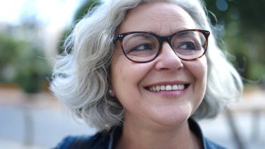 Middle age woman with grey hair smiling confident at street