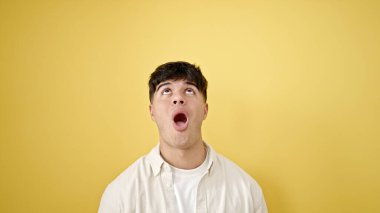 İspanyol asıllı genç adam, şaşırmış bir ifadeyle izole edilmiş sarı arka plana bakıyor.