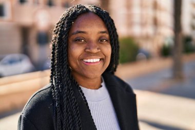 Afro-Amerikalı kadın parkta kendinden emin bir şekilde gülümsüyor.