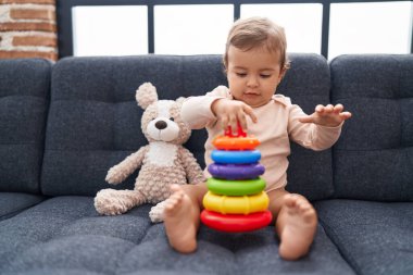Sevimli İspanyol bebek evdeki kanepede oturmuş basketbol oynuyor.