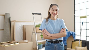 Young beautiful hispanic woman smiling confident standing with arms crossed gesture at new home