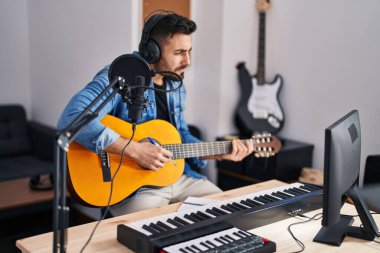 Genç İspanyol bir adam müzik stüdyosunda klasik gitar çalarak şarkı söylüyor.