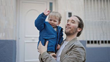 Baba oğul gülümsüyor. Kendilerine güveniyorlar. Sokakta sarılıyorlar.