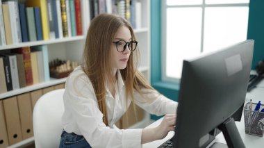 Young blonde woman student using computer studying at university classroom