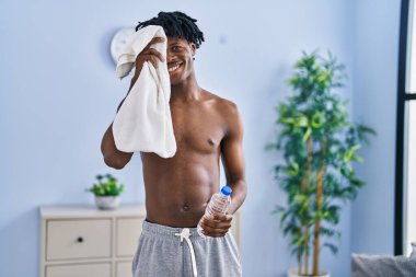 Afrika kökenli Amerikalı sporcu evinde su ve havlu tutuyor.