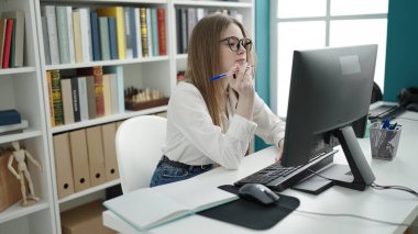 Young blonde woman student using computer studying at university classroom