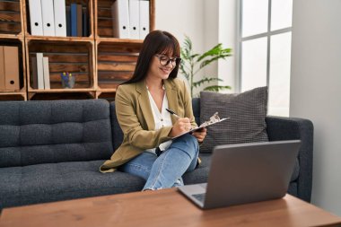 Genç ve güzel İspanyol kadın psikolog psikoloji kliniğinde online seans yapıyor.