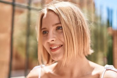 Young blonde woman smiling confident looking to the side at street