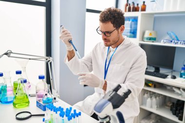 Genç İspanyol bilim adamı laboratuarda test tüpüne sıvı döküyor.