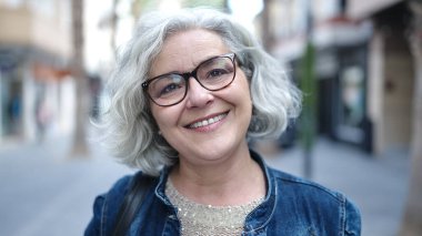 Middle age woman with grey hair smiling confident at street