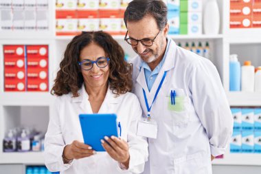 Eczanede çalışan erkek ve kadın eczacılar dokunmatik ped kullanıyorlar.