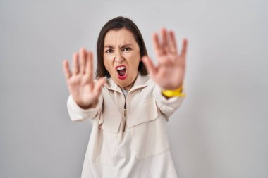 Middle age hispanic woman standing over isolated background doing stop gesture with hands palms, angry and frustration expression 