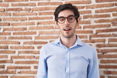 Duvarın arkasında duran genç İspanyol adam kameraya seksi bir ifadeyle bakıyor, neşeli ve mutlu bir yüzle.. 