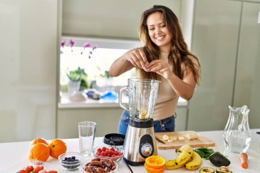 Genç, güzel İspanyol kadın mutfakta sebze suyu ve blender hazırlıyor.