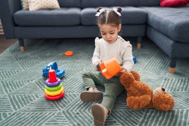 Sevimli İspanyol kız evde yerde oturmuş oyuncaklarla oynuyor.