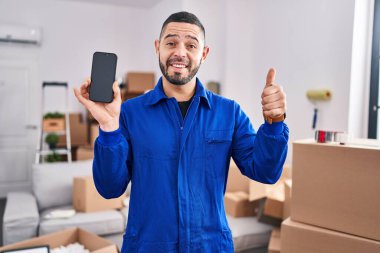 İspanyol adam hareket servisi üzerinde çalışıyor. Akıllı telefon ekranında gülümsüyor, gülümsüyor ve olumlu bakıyor. 