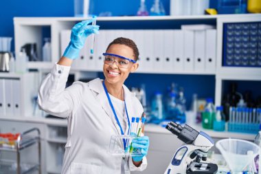 Laboratuvarda test tüpleri tutan Afrikalı Amerikalı kadın bilim adamı.
