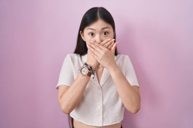 Pembe arka planda duran Çinli genç bir kadın yanlışlıkla ağızlarını kapatarak şok geçirdi. gizli kavram. 