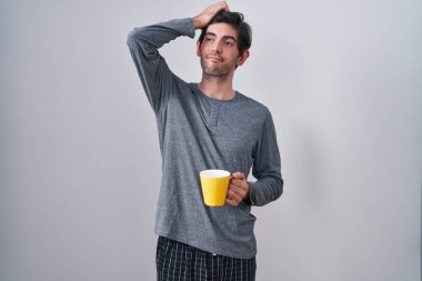 Pijama giyen, kahve içen, kafası karışmış ve soru soran genç İspanyol bir adam. Şüpheyle kararsız, kafa kafaya düşünerek. Düşünceli kavram. 