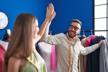 Erkek ve kadın terziler giyim fabrikasında elleri havada beşlik çakıyor.