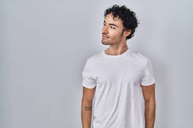 Soyutlanmış arka planda duran İspanyol bir adam yüzünde gülümseme, doğal bir ifade ile yan yana bakıyor. Kendinden emin gülen. 