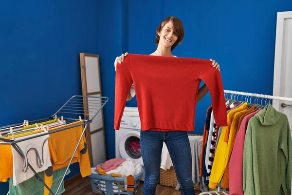 Joven Hermosa Mujer Hispana Sonriendo Confiada Sosteniendo Suéter Perchero Ropa —  Fotos de Stock