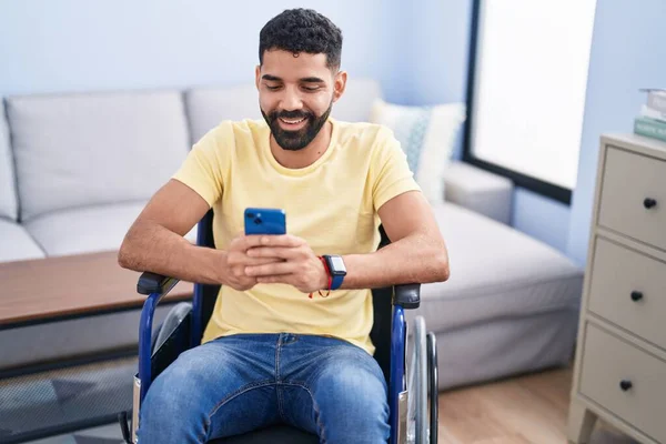 Hombre Árabe Joven Usando Teléfono Inteligente Sentado Silla Ruedas Casa — Foto de Stock