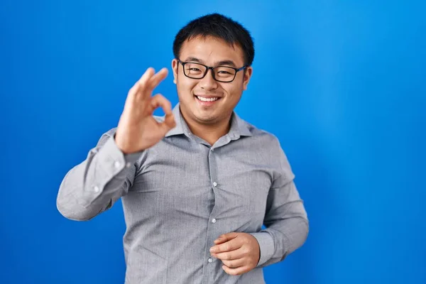 Fiatal Kínai Férfi Áll Kék Háttér Felett Mosolyogva Pozitív Csinál — Stock Fotó