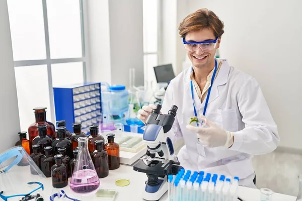 Young Caucasian Man Scientist Using Microscope Holding Plant Sample Laboratory — Stockfoto