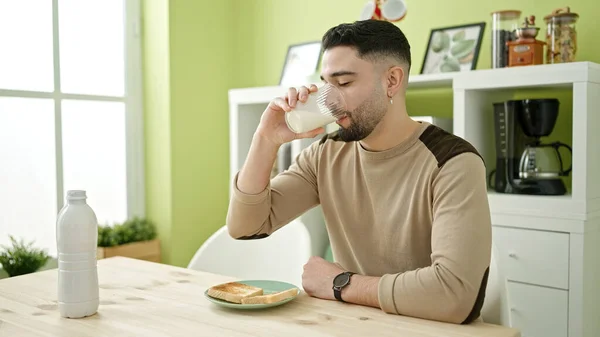 Hombre Árabe Joven Bebiendo Vaso Leche Sentado Mesa Casa —  Fotos de Stock