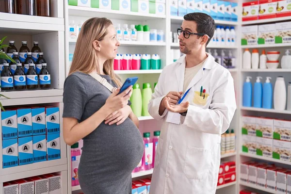 男女药剂师和孕妇病人在药店用智能手机讲话 — 图库照片
