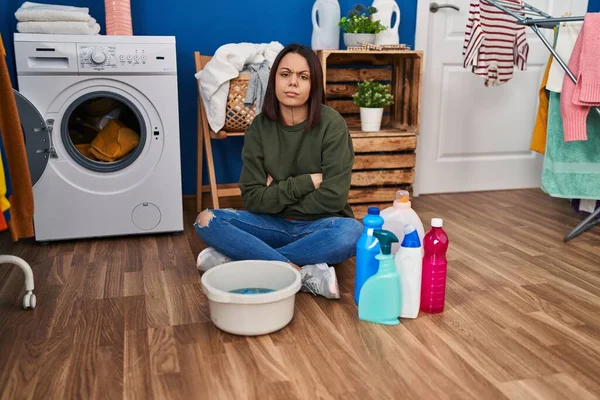 Young hispanic woman doing laundry washing by hand skeptic and nervous, disapproving expression on face with crossed arms. negative person.