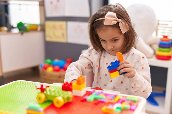 stock image Adorable hispanic girl playing with construction blocks sitting on table at kindergarten