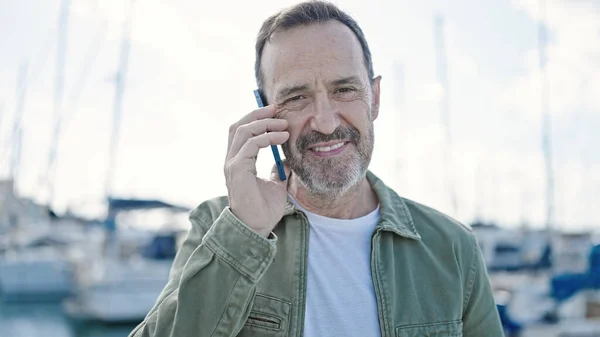 ポートでスマートフォンで自信を持って話して笑顔中年の男 — ストック写真