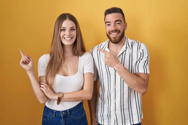 Sarı Arka Planda Duran Genç Çift Yüzünde Kocaman Bir Gülümsemeyle — Stok fotoğraf