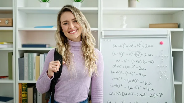 Young blonde woman student smiling confident wearing backpack at classroom