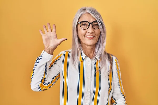 Sarı Arka Planda Duran Gri Saçlı Orta Yaşlı Bir Kadın — Stok fotoğraf