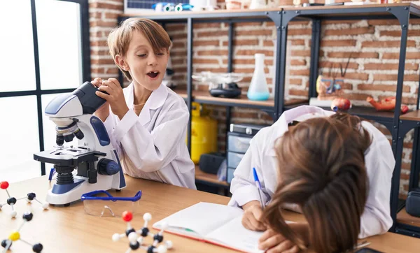 Entzückende Jungenschüler Schreiben Labor Notizen Unter Dem Mikroskop — Stockfoto