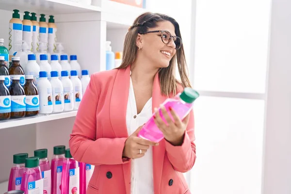 Young Hispanic Woman Customer Smiling Confident Holding Shampoo Bottle Pharmacy — Stock Photo, Image