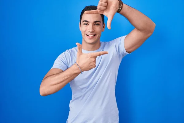 Jeune Homme Hispanique Debout Sur Fond Bleu Souriant Faisant Cadre — Photo