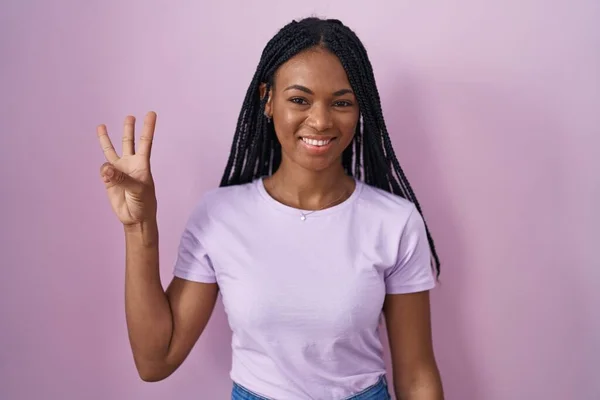 Африканская Американка Косичками Стоящая Розовом Фоне Показывающая Пальцами Номер Три — стоковое фото